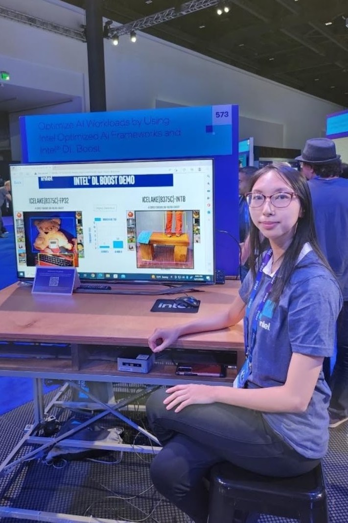 Joanna at the Intel DL Boost demo booth at Intel Innovation 2022, beside a screen comparing FP32 and INT8 inference
